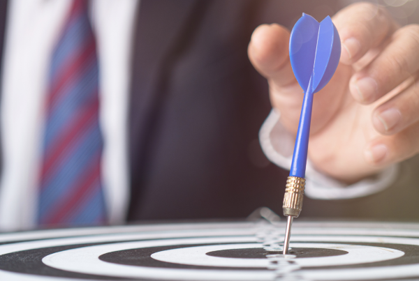 A hand reaches out for a dart on the center of a target. Compliance is important for any business.